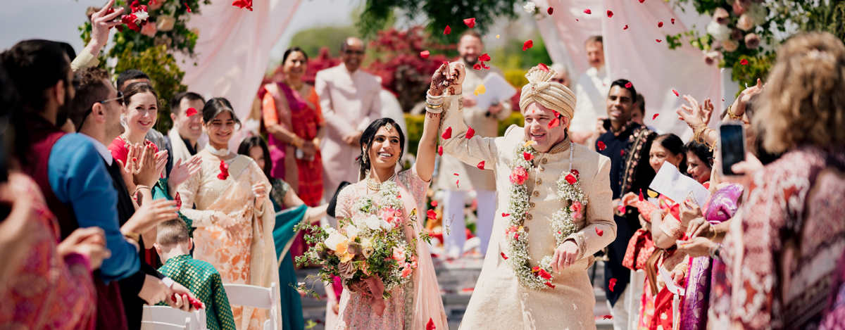 Joyful Indian fusion couple in wedding attire, celebrating their NJ wedding recessional.