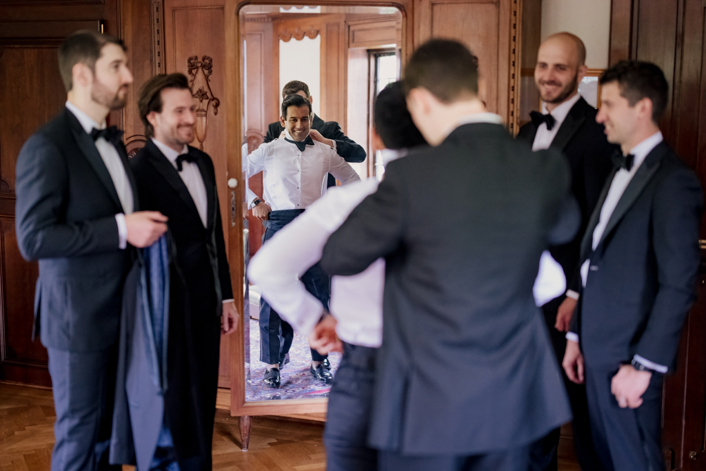Candid photo of groomsmen helping the groom get ready at Pleasantdale Chateau in NJ
